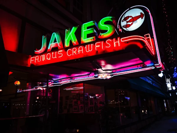 Jakes Famous Crawfish neon sign glowing green at night — Noir10 handmade LED backlit print